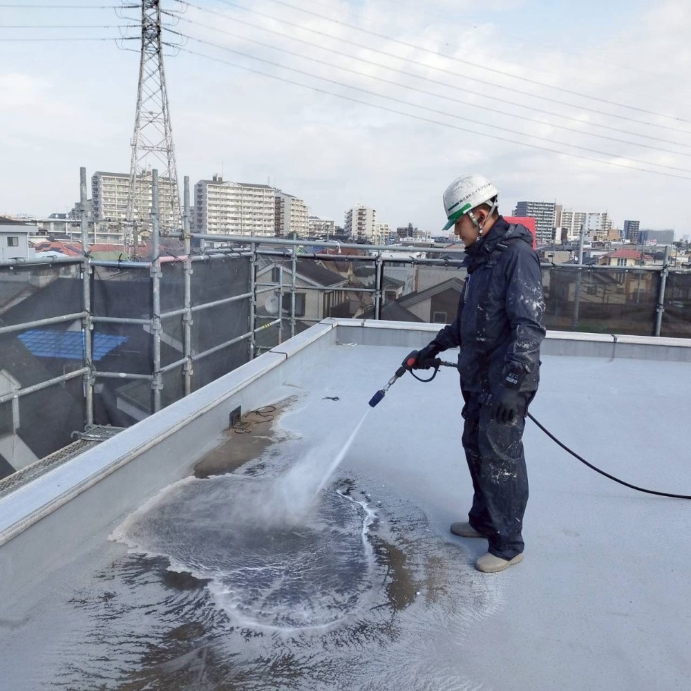 屋上防水工事に先立ち、高圧洗浄で汚れや脆弱な旧塗膜を除去し、防水材が密着しやすい下地へ整えます。 写真