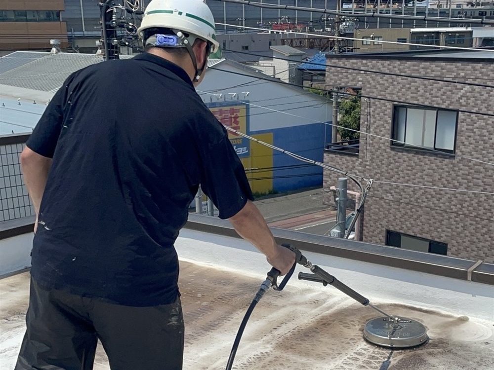 高圧洗浄で屋上の汚れや付着物を丁寧に除去し、防水施工に適した下地を整えます。 写真